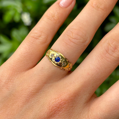 Antique, Edwardian sapphire and diamond three-stone gypsy ring worn on hand.