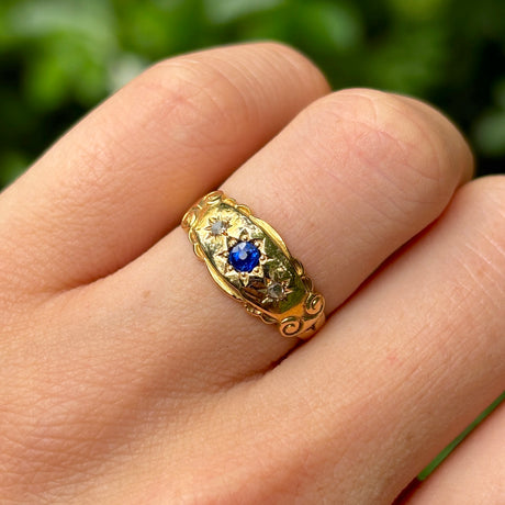 Antique, Edwardian sapphire and diamond three-stone gypsy ring worn on hand.