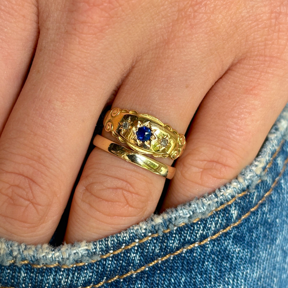 Antique, Edwardian sapphire and diamond three-stone gypsy ring worn on hand.