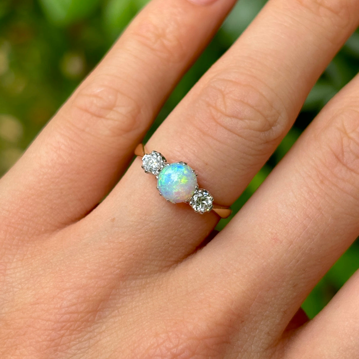 Antique, Edwardian opal and diamond three-stone ring on hand