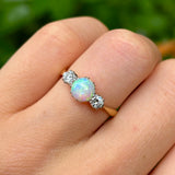 Antique, Edwardian opal and diamond three-stone ring on hand.