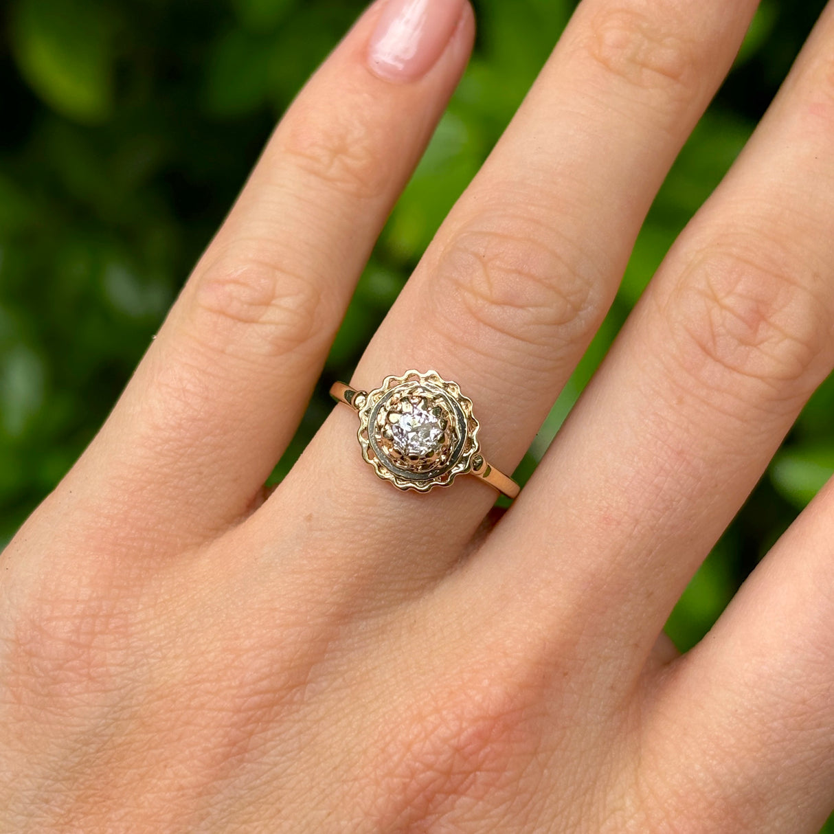 Vintage, solitaire diamond engagement ring worn on hand.