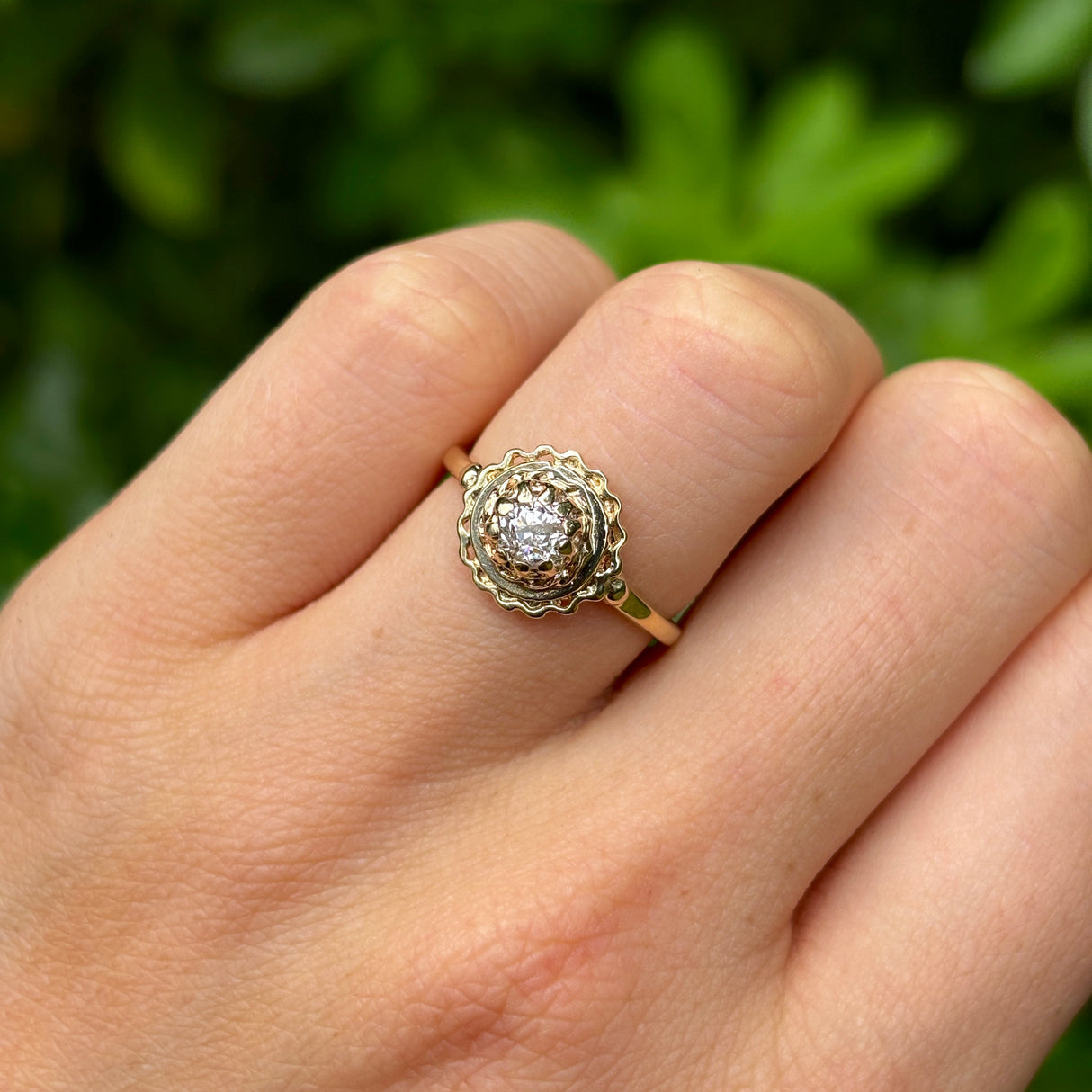 Vintage, solitaire diamond engagement ring worn on hand.