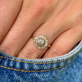 Vintage, solitaire diamond engagement ring worn on hand in pocket of jeans.