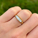 Antique, Edwardian five-stone diamond ring worn on hand.