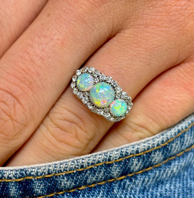 Antique, Victorian three-stone opal & diamond cluster ring worn on hand.