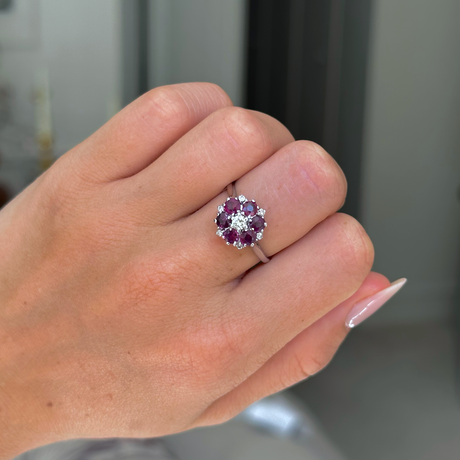 ruby and diamond cluster ring worn on closed hand, front view. 