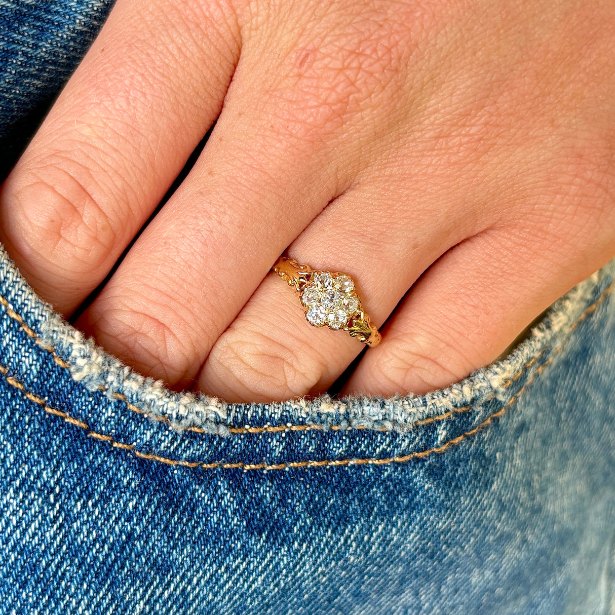 2093-Antique, Edwardian diamond daisy cluster ring held in fingers 