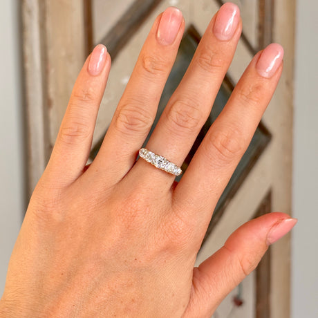 Antique, Edwardian five-stone diamond ring worn on hand.