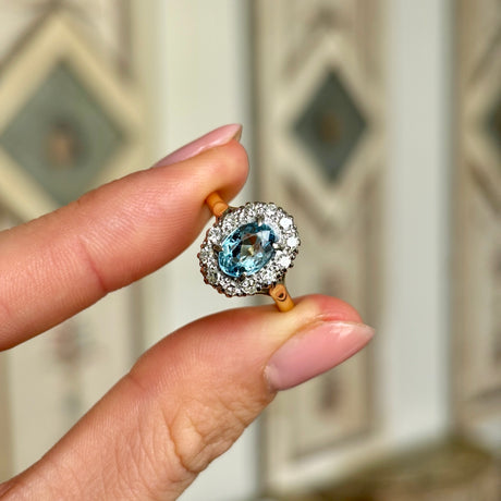 Antique, Edwardian blue topaz & diamond cluster ring held in fingers