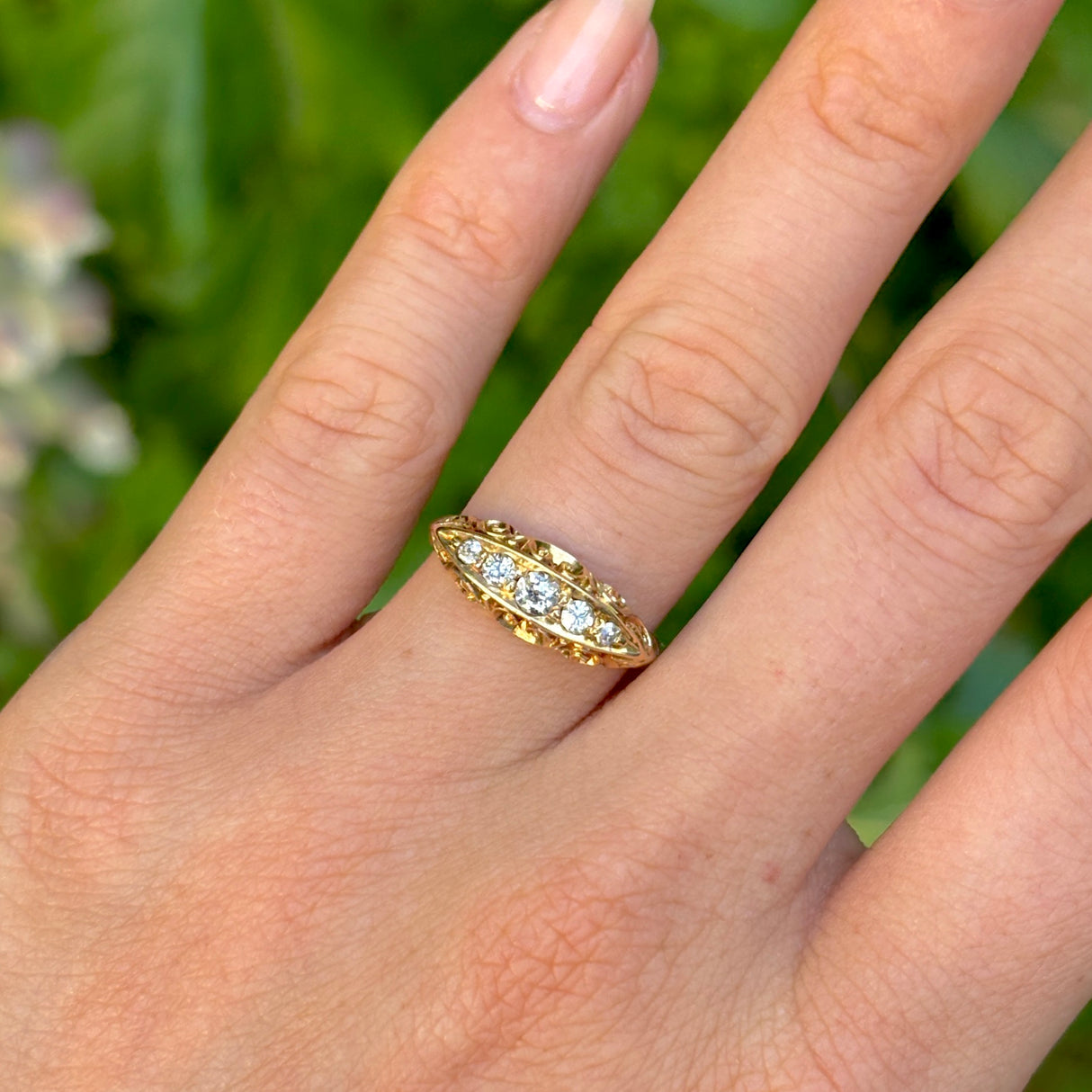 Antique, Edwardian five-stone diamond ring worn on hand.