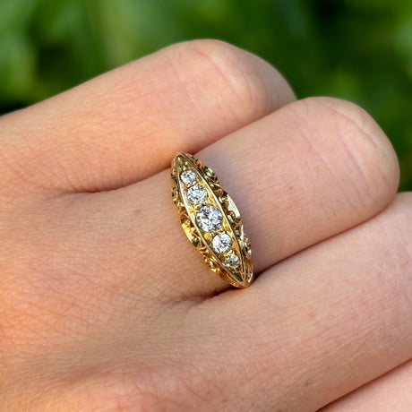 Antique, Edwardian five-stone diamond ring worn on hand.