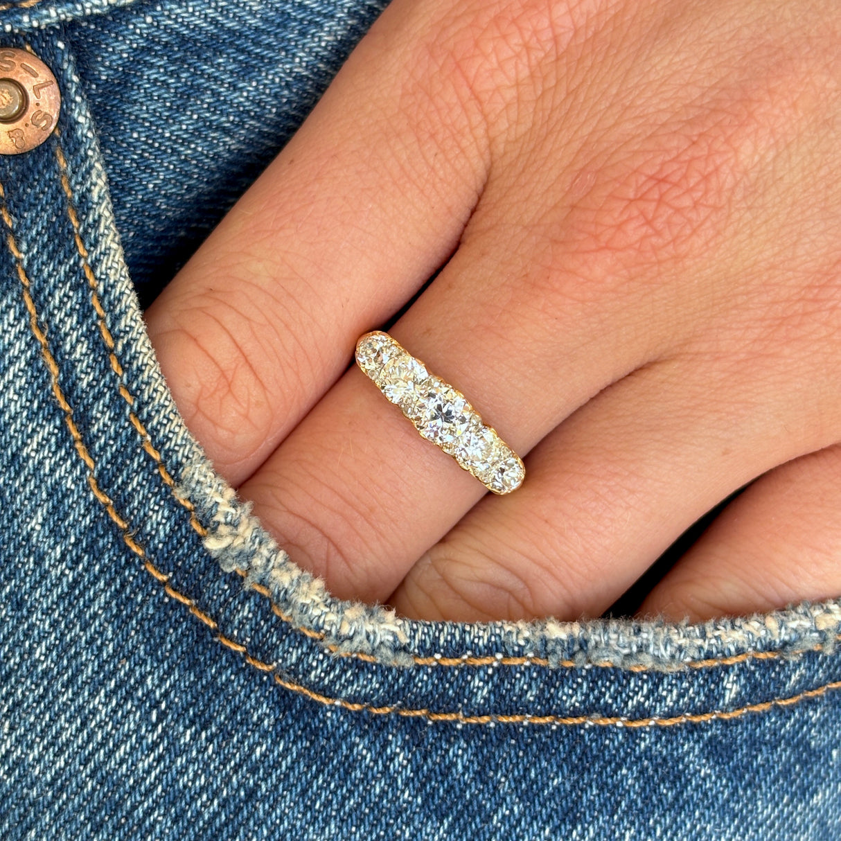 Antique, Edwardian five-stone diamond ring worn on hand.