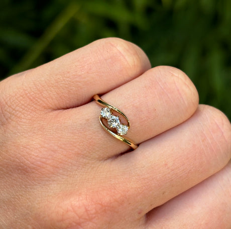 Antique, Edwardian three-stone diamond twist ring worn on hand.