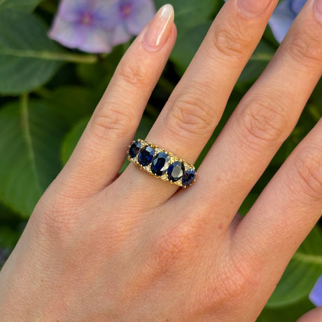 Antique, Victorian five stone sapphire ring worn on hand.