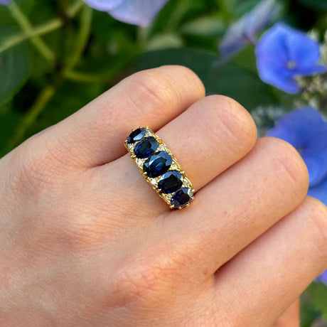 Antique, Victorian five stone sapphire ring worn on hand.