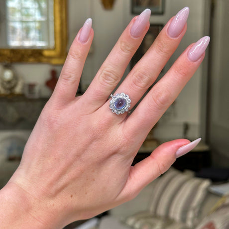 cabochon sapphire and diamond cluster ring set in platinum on hand. 