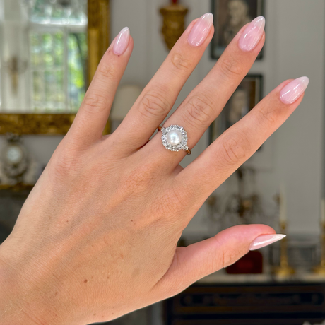 Antique pearl and diamond cluster ring worn on hand. 