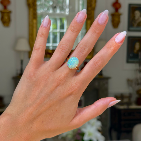 cabochon white opal cocktail ring with 18ct yellow gold band, worn on hand, front view. 