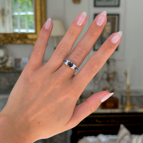 Antique purple sapphire and diamond engagement ring, worn on hand, front view.