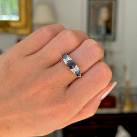 Antique purple sapphire and diamond engagement ring, worn on closed hand, front view.