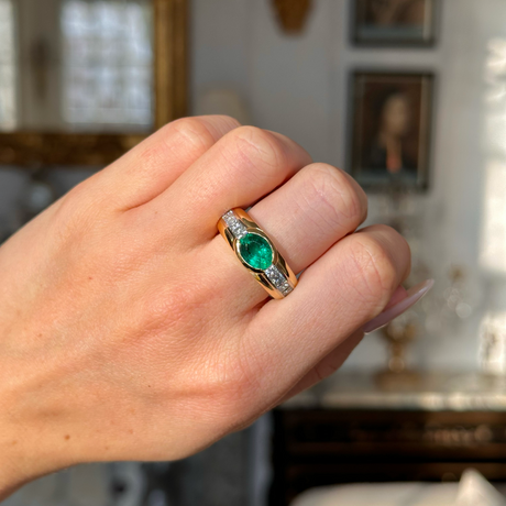 Vintage emerald and diamond band worn on closed hand. 