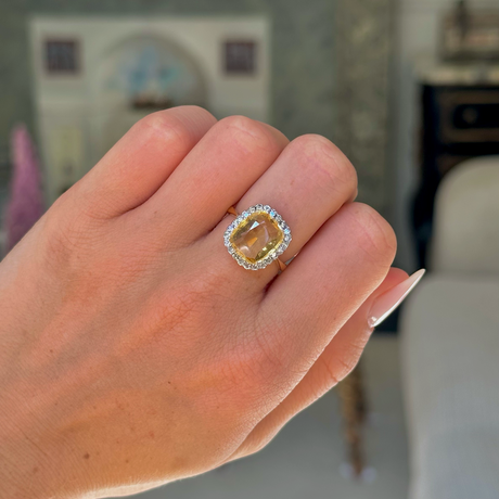 Yellow sapphire and diamond cluster ring,  worn on closed hand,front view. 