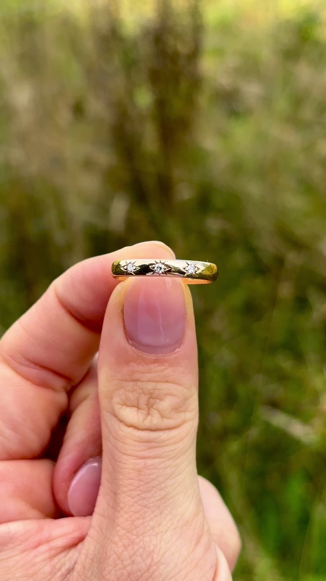 Vintage, 1960s three-stone diamond band worn on hand held in fingers.