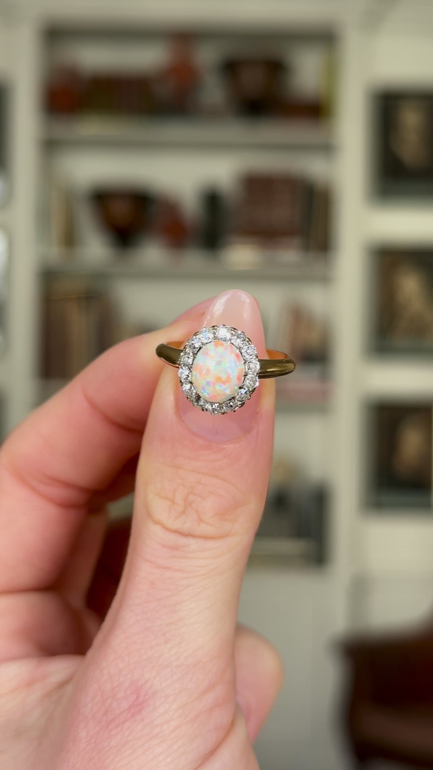 Antique, Edwardian White Opal and Diamond Cluster Ring held in fingers and rotated to give perspective.