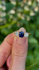 Vintage, 1980s sapphire and diamond three-stone ring worn held in fingers.