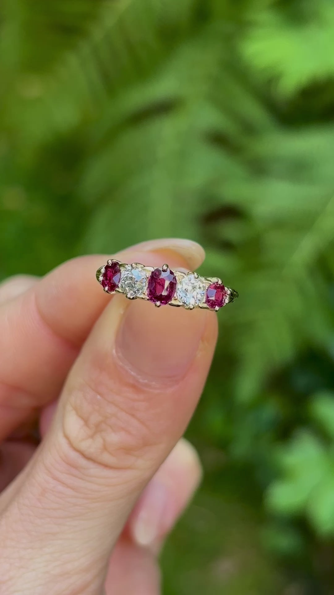 Antique, Victorian ruby & diamond five-stone ring held in fingers.