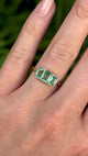 Vintage, 1930s three-stone emerald ring worn on hand.