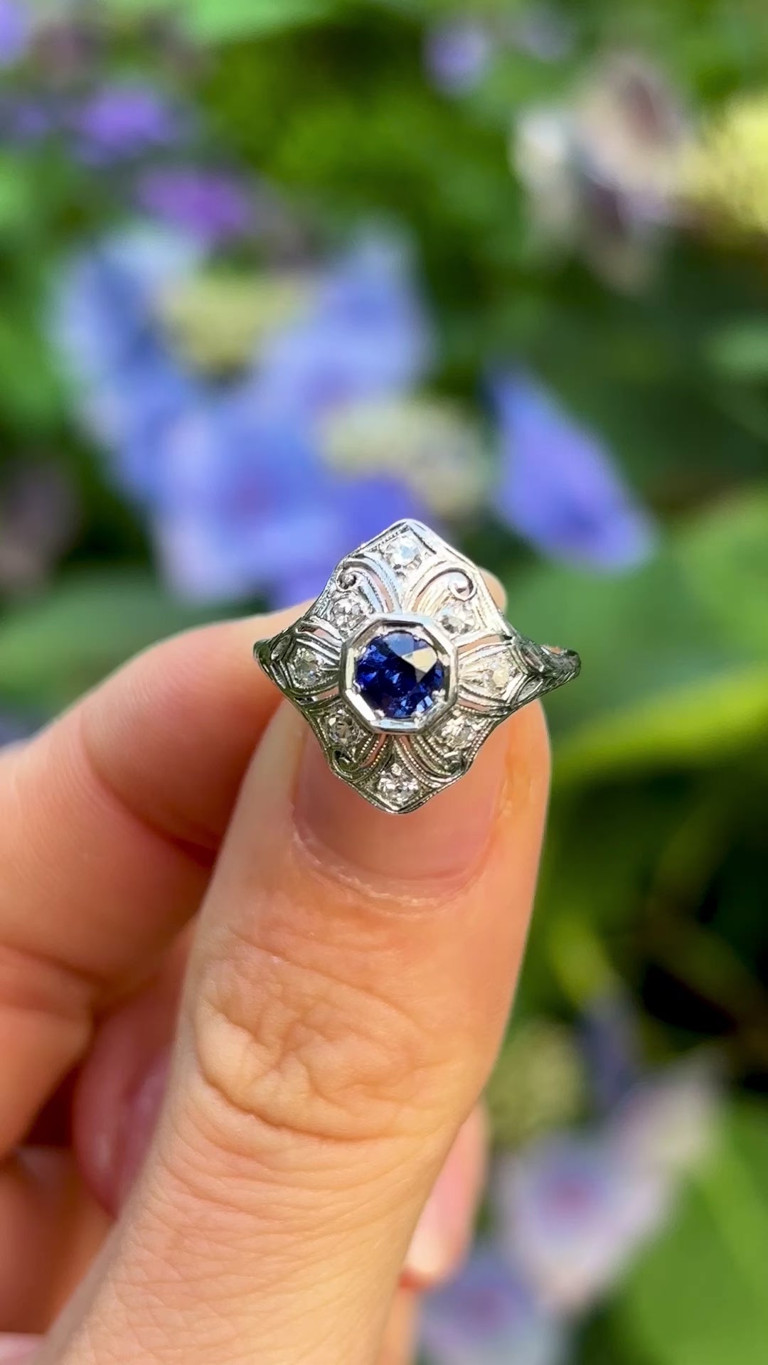 Vintage, 1930s sapphire and diamond ring held in fingers.