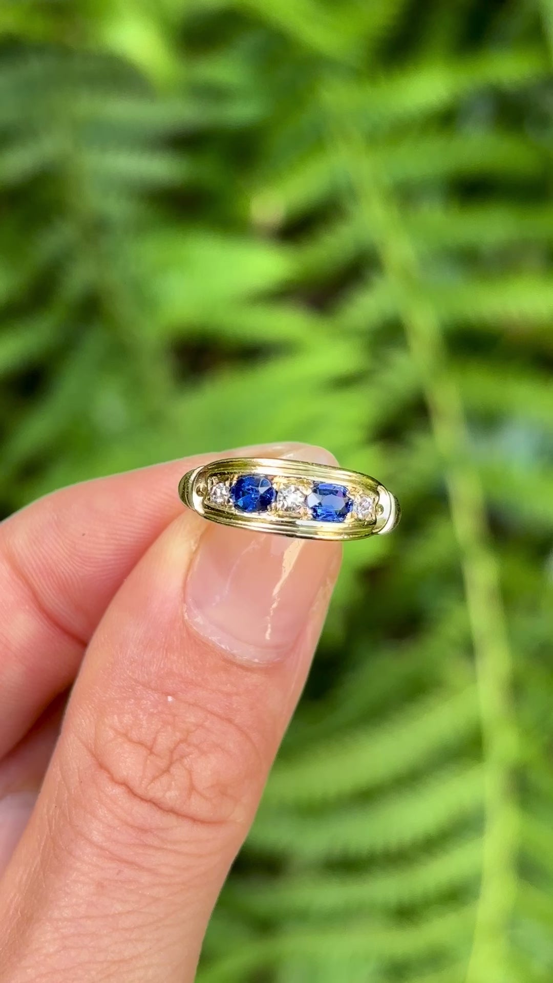 Vintage, Art Deco sapphire & diamond five-stone ring held in fingers.