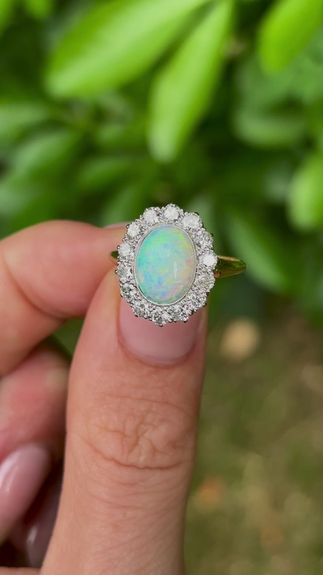 Antique, Edwardian opal & diamond cluster held in fingers.