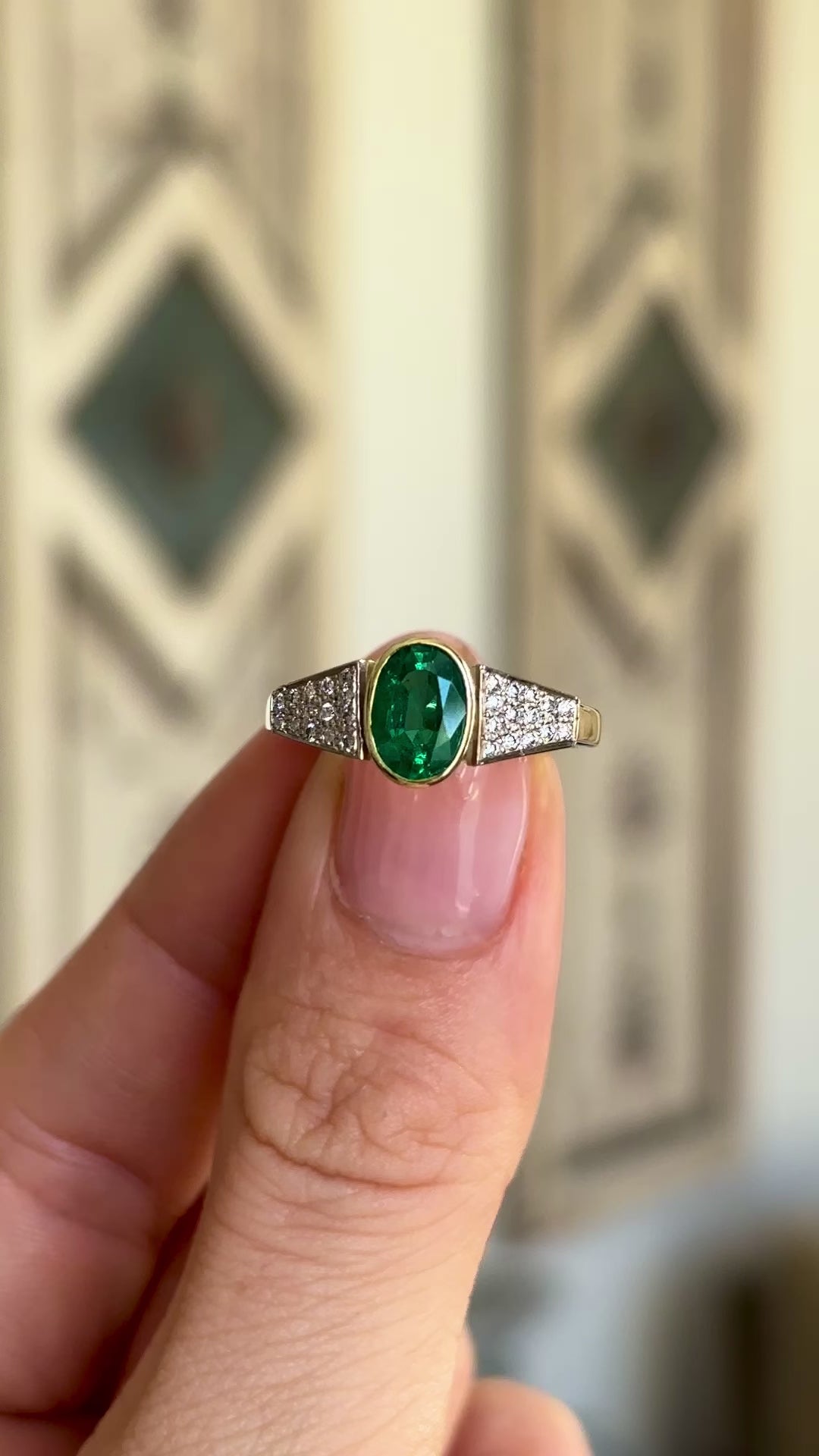 Vintage, 1970s inspired emerald & diamond ring held in fingers.