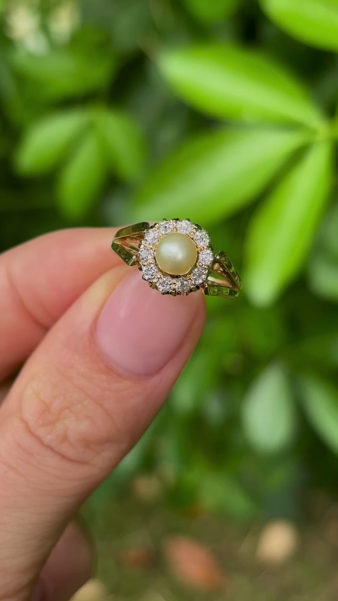 Vintage, 1980s pearl & diamond cluster ring held in fingers.