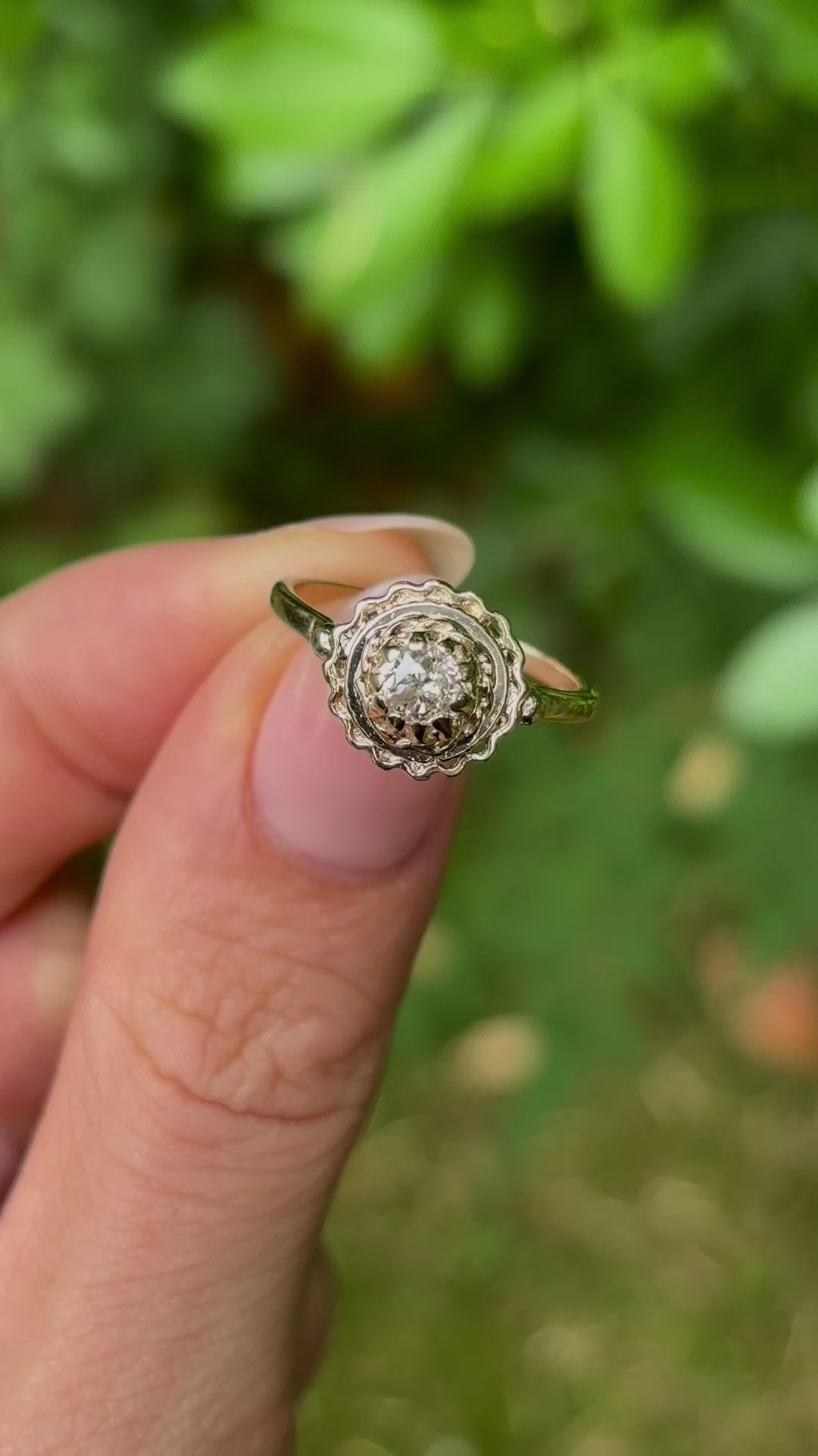 Vintage, solitaire diamond engagement ring held in fingers.