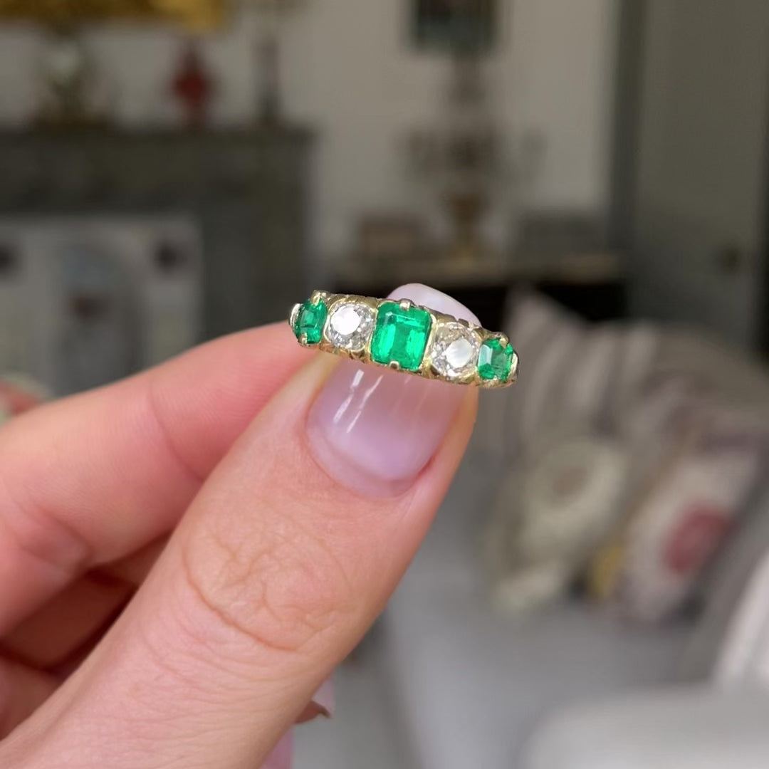 Five stone emerald and diamond ring held in fingers and moved around to give perspctive.
