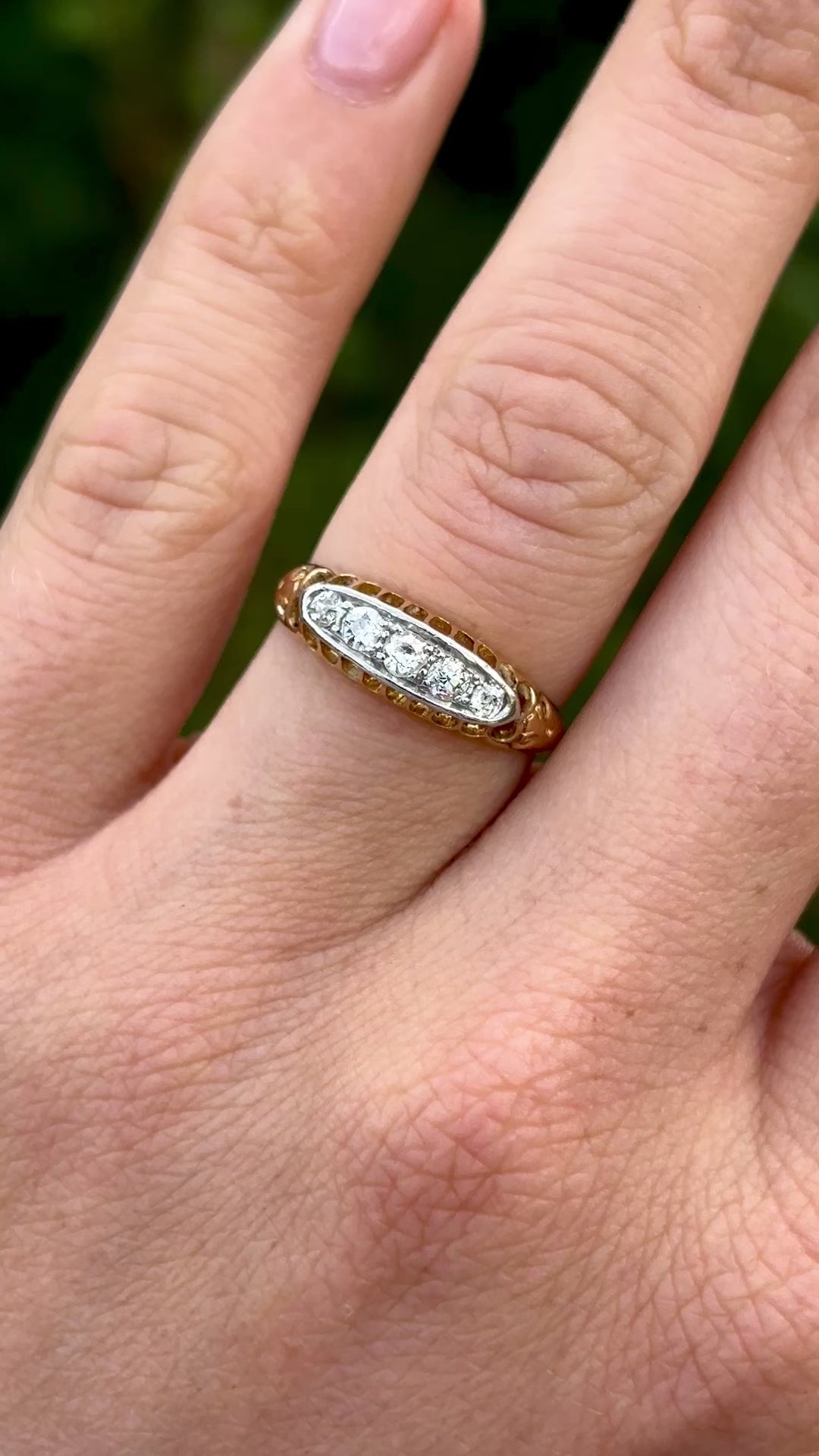 Antique, Edwardian five-stone diamond ring worn on hand.