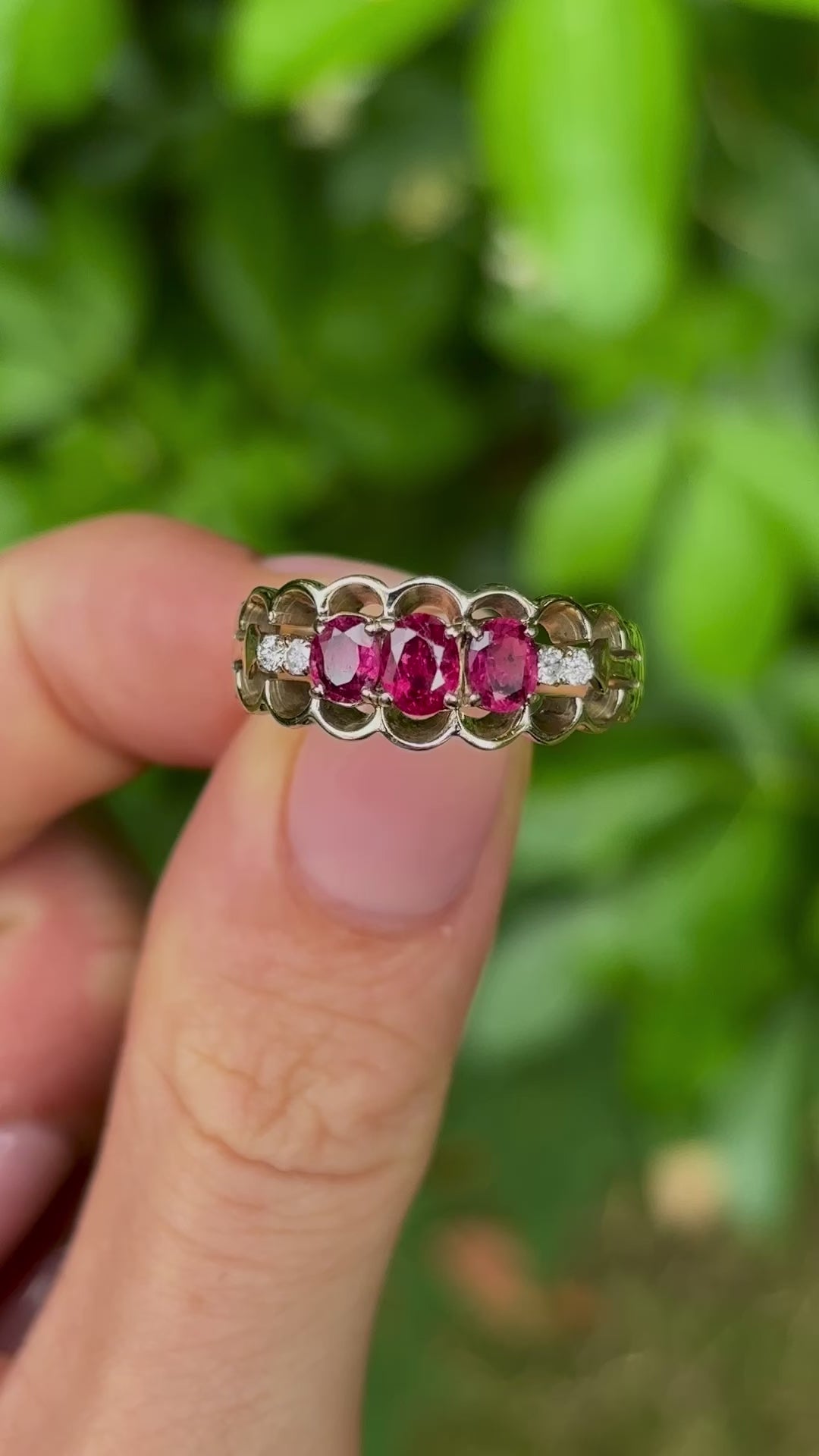 Vintage, 1980s ruby and diamond three-stone ring held in fingers.