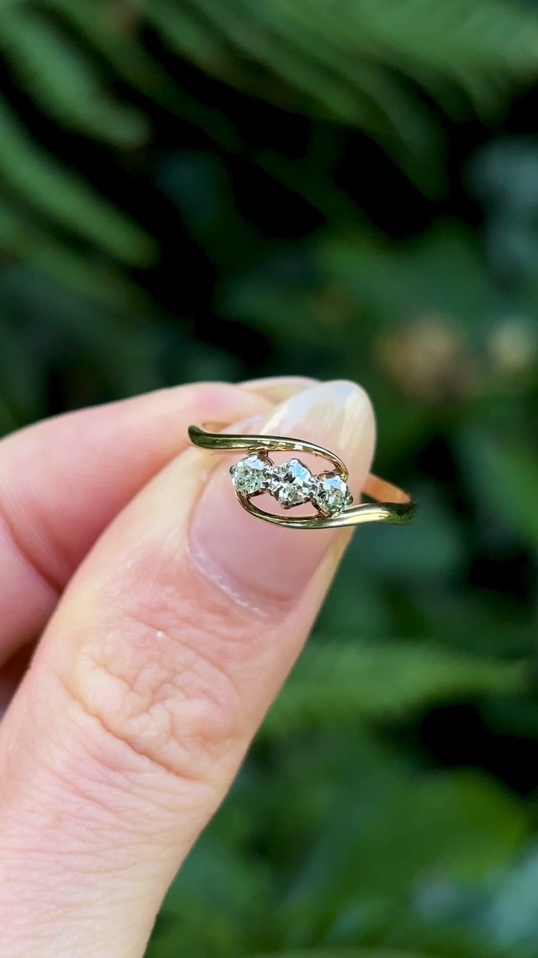 Antique, Edwardian three-stone diamond twist ring held in fingers.