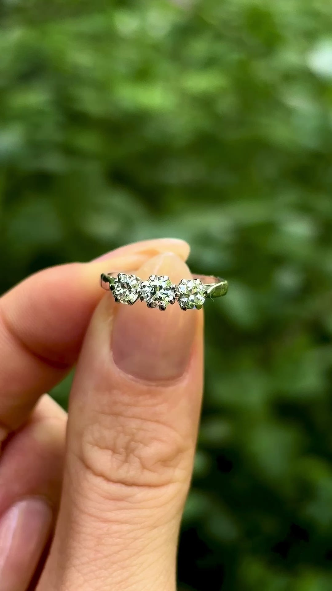 Vintage, 1980s three-stone diamond ring, platinum held in fingers