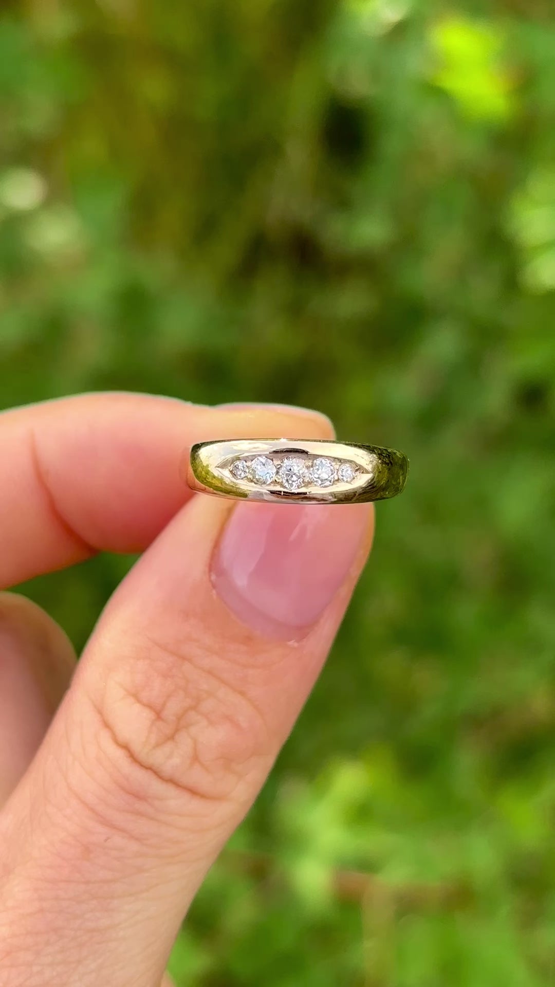 Antique, Edwardian five-stone diamond ring held in fingers