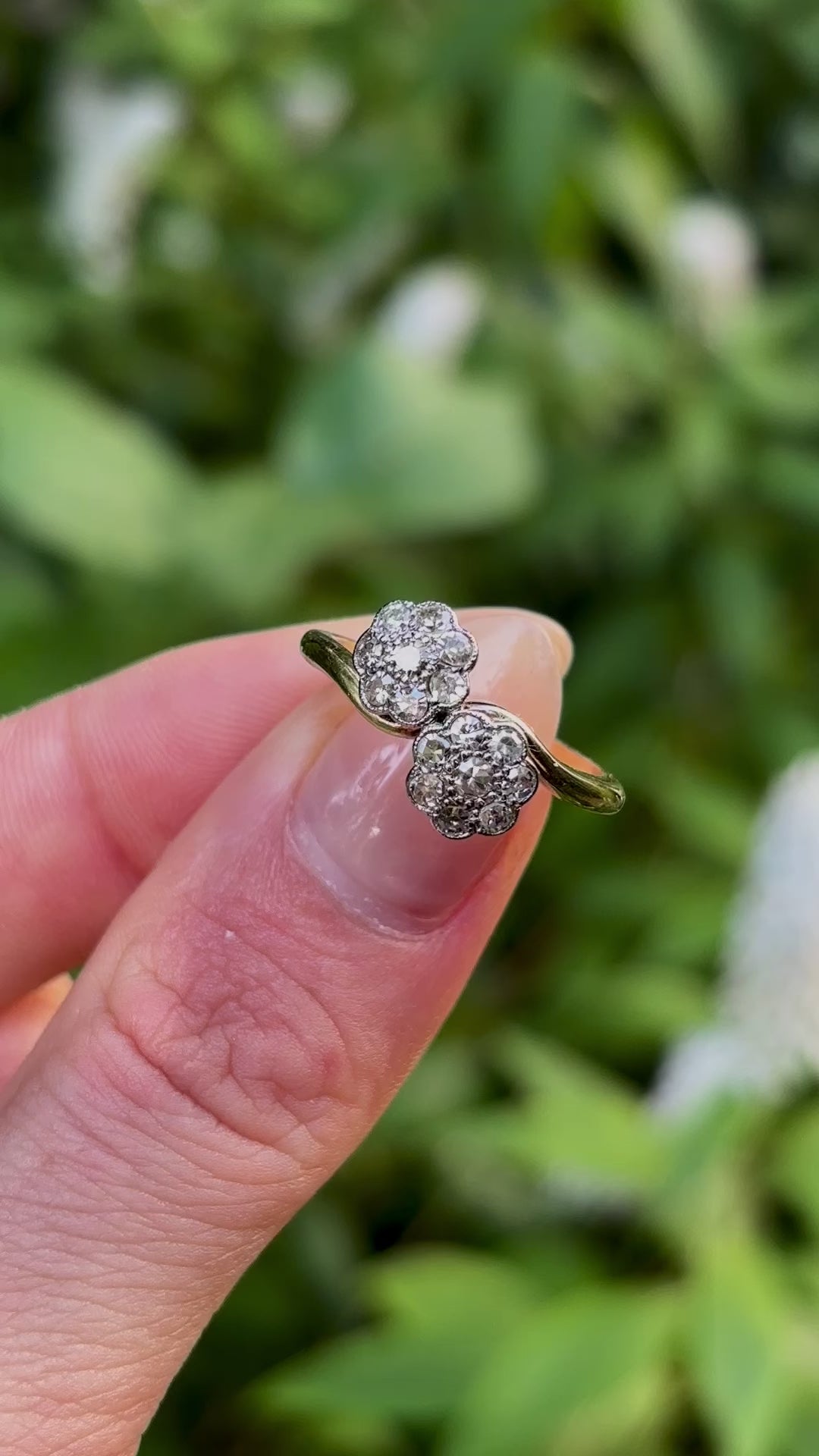 Antique, Edwardian diamond cluster ring held in fingers.