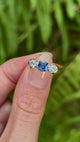 Antique, Edwardian sapphire and diamond three-stone engagement ring held in fingers.