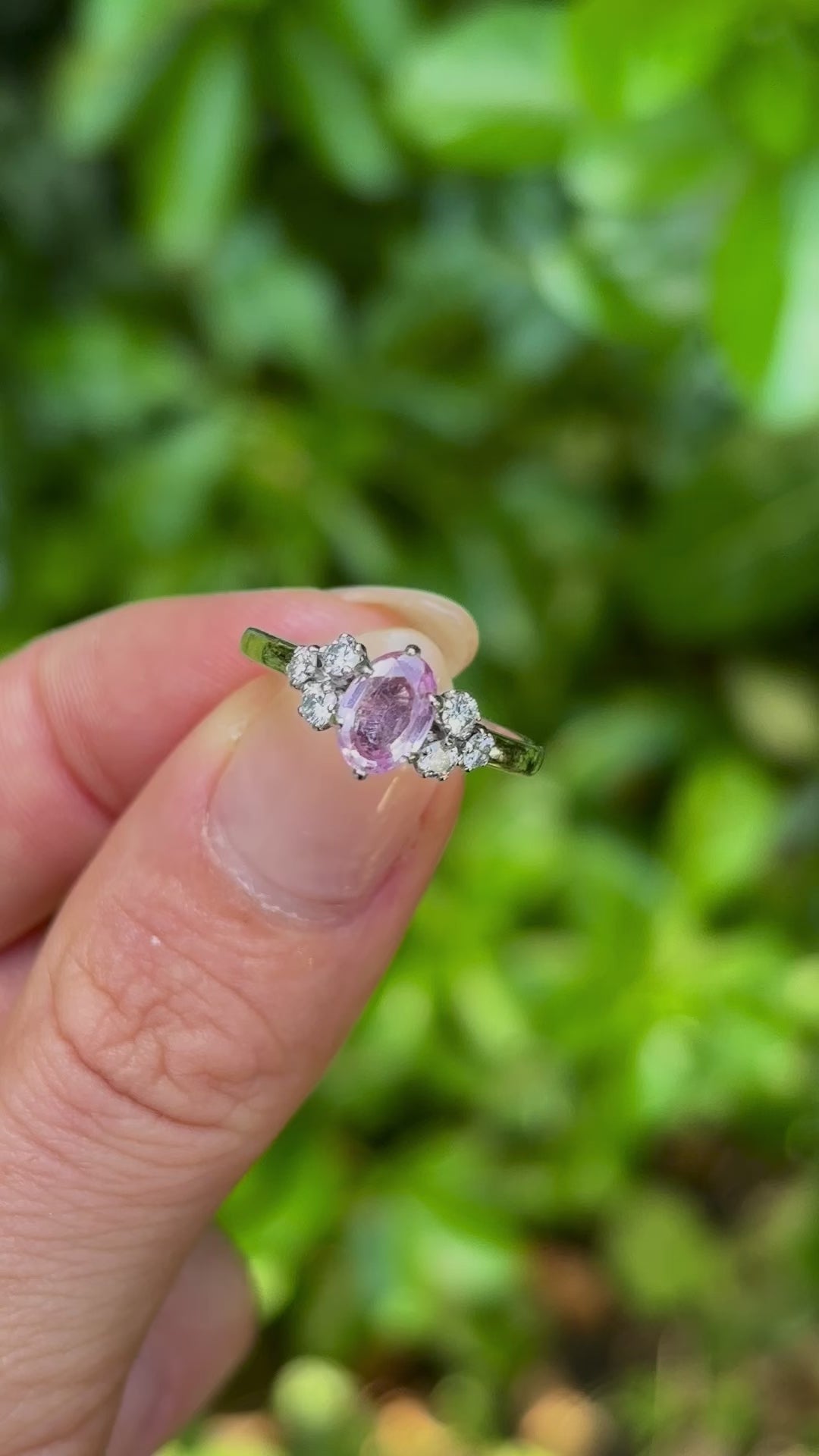 Vintage, 1970s pink sapphire & diamond ring held in fingers.