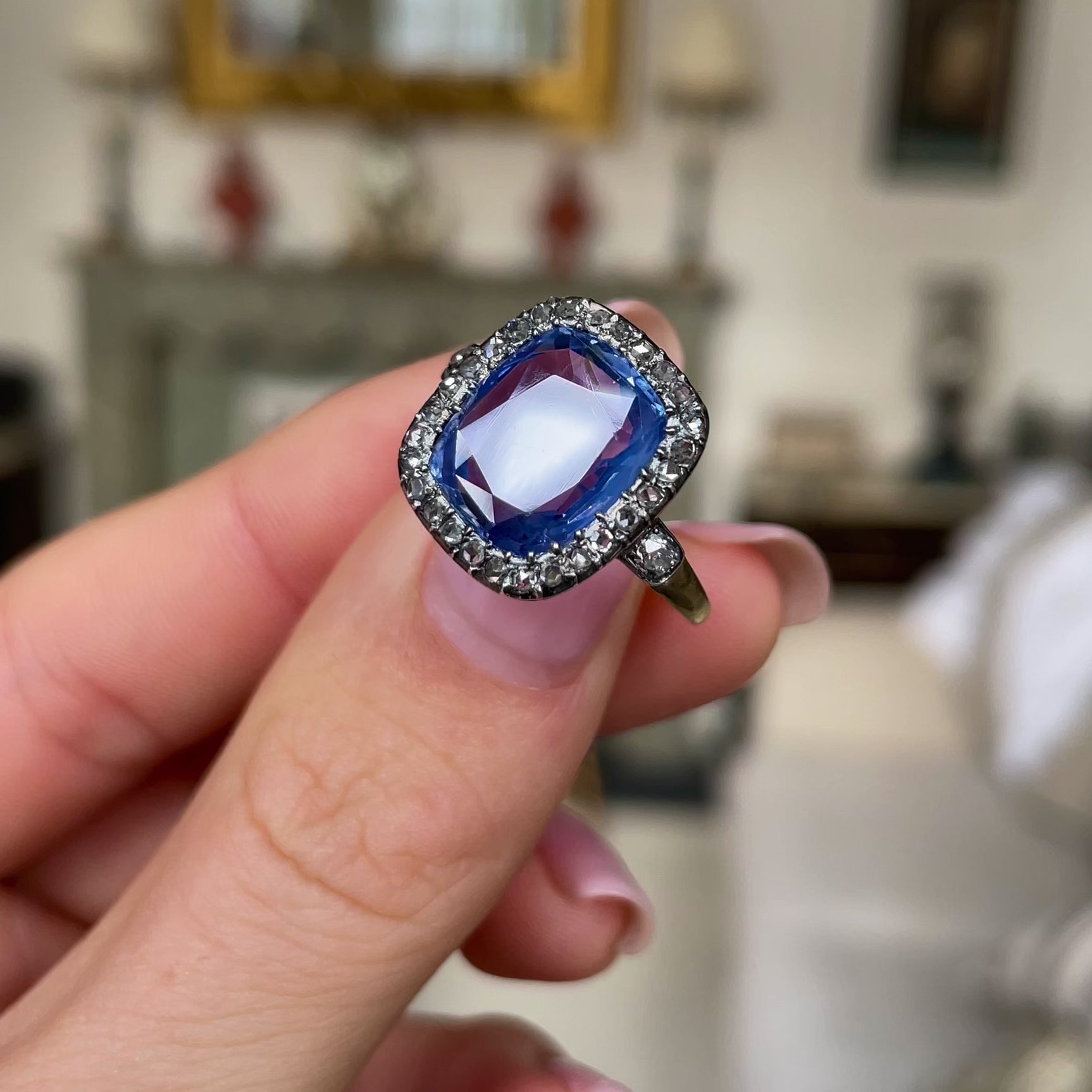 Early Victorian sapphire and diamond engagement ring, held in fingers and rotated to give perspective.