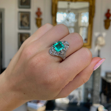 Art Deco emerald and diamond ring, worn on hand.