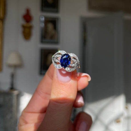 Art Nouveau, sapphire and diamond ring, held in fingers.